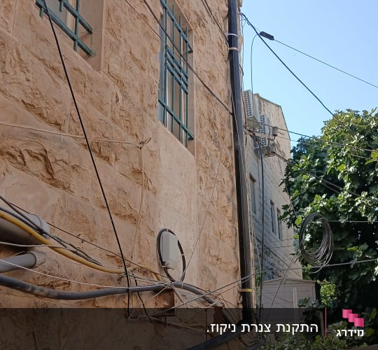 התקנת צנרת אינסטלציה ומרזב חיצוני על חזית בניין אבן בגובה